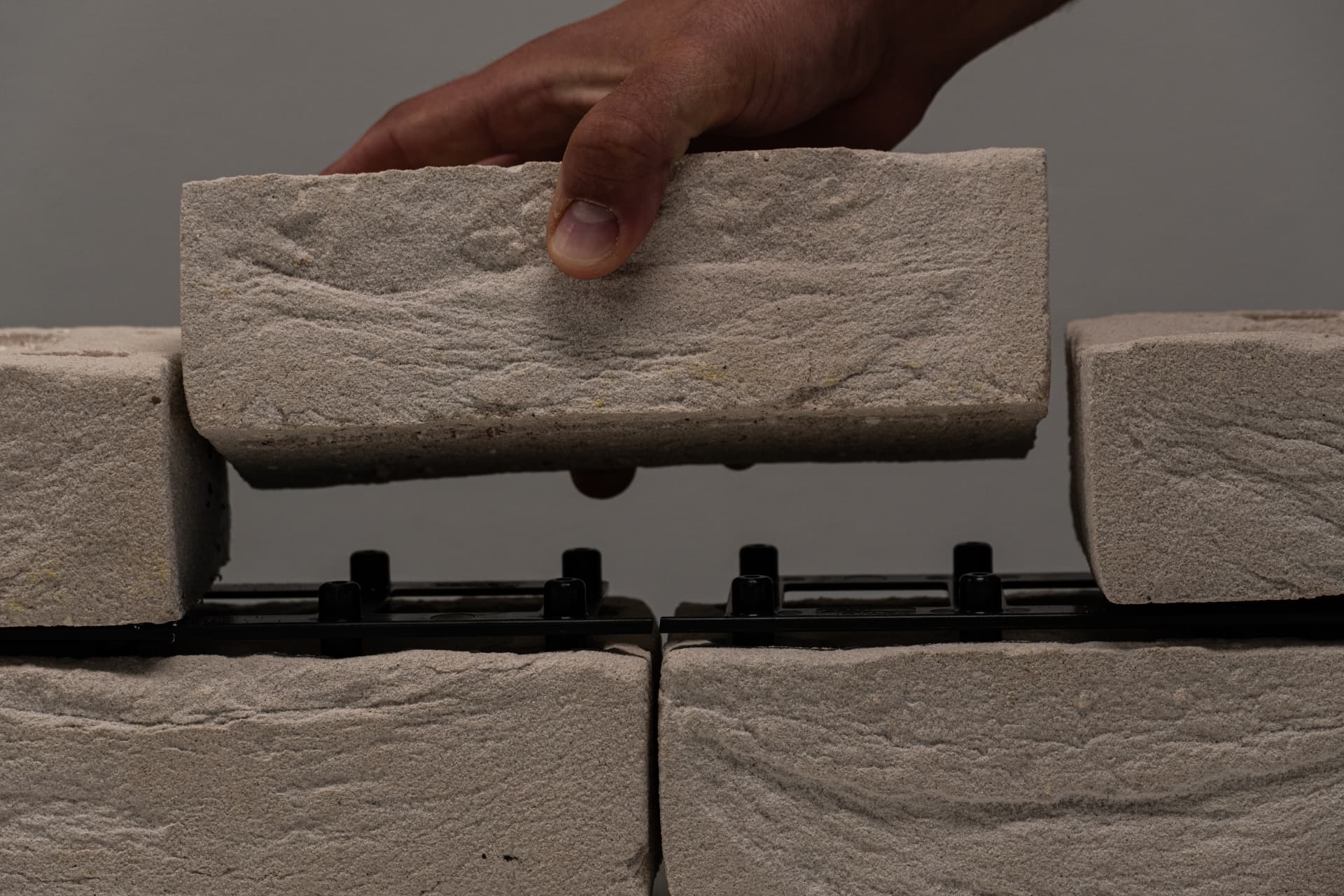 Hand plaatst baksteen op Drystack kliksysteem