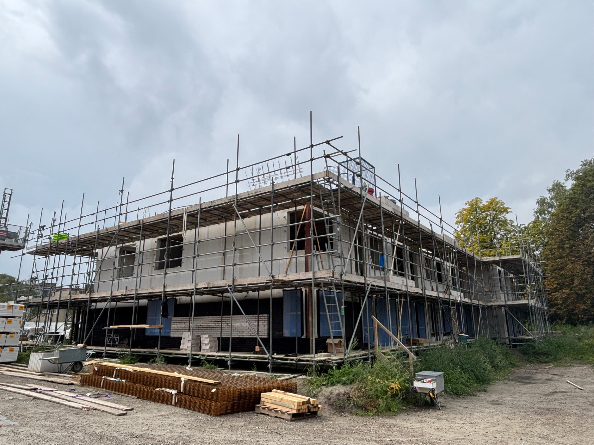 24 appartementen Hengelo, gebouw in aanbouw achter steiger met materiaal op de grond